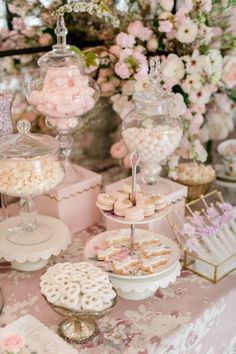 a table topped with lots of desserts next to a vase filled with pink flowers