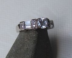 an engagement ring with three baguettes and two side stones on top of a rock