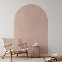 a chair sitting next to a book on top of a wooden floor in front of a wall