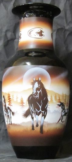 a black vase with horses painted on it