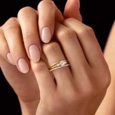 a woman's hand with two rings on her fingers and one holding the other