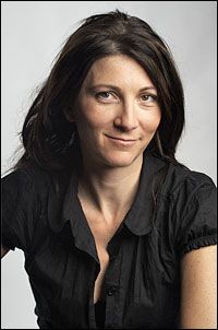 a woman is smiling and posing for the camera with her hands on her hips, wearing a black shirt