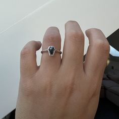 a woman's hand with a diamond ring on top of her finger, next to a couch