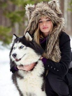 a woman is hugging her husky dog in the snow