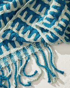 a blue and white knitted blanket laying on top of a table