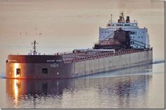 a large cargo ship in the water at sunset