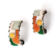 two pairs of earrings with the colors of india and ireland painted on them, sitting next to each other