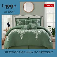 a bed with green comforter and pillows in front of a blue poster for sale