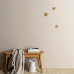 a wooden table sitting next to a white vase on top of a hard wood floor