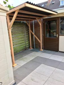 an outdoor covered patio area with wooden posts and wood slats on the side of it