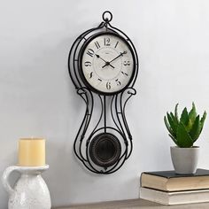 a clock is hanging on the wall next to a potted plant and a candle