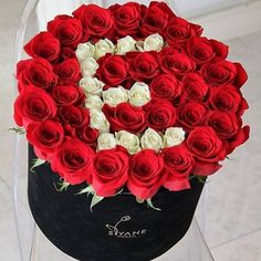 a large bouquet of red and white roses in a black hat box with the letter e on it