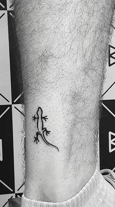 a small lizard tattoo on the ankle is shown in this black and white photo,