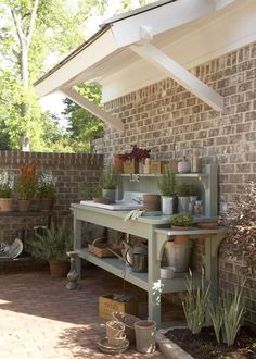 an outdoor kitchen with potted plants and pots on the stove top in front of a brick wall