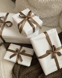 three wrapped presents sitting on top of a bed