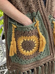 a woman is holding a crocheted bag with tassels