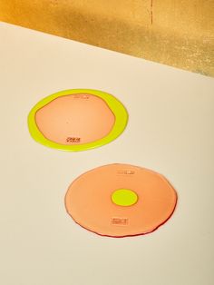 two orange and yellow plates sitting on top of a white counter next to each other