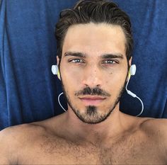 a shirtless man with earphones on his head is laying in a blue chair