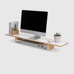 a computer monitor sitting on top of a wooden shelf next to a potted plant