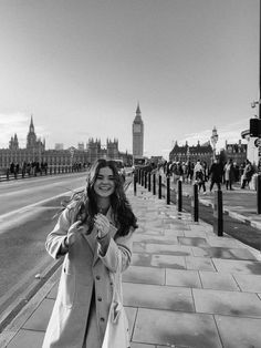 a woman standing on the sidewalk in front of big ben