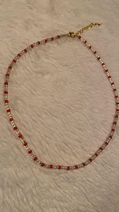 a red and silver beaded necklace on a white furnishing area with a gold plated chain