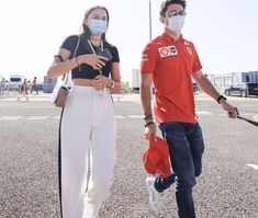 a man and woman walking down the street wearing face masks