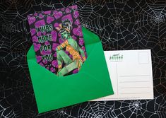 there is a green envelope with an image of a zombie in it and some spider webs on the table