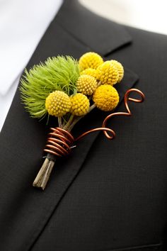 a boutonniere with yellow flowers and green grass on it's lapel