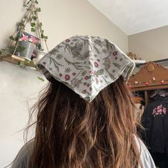 a woman with long brown hair wearing a white and grey floral print hat on top of her head