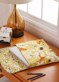 an orange table with a yellow and white flowered cloth on it next to a lamp