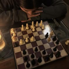 a man sitting at a table with his hands on his face as he plays chess