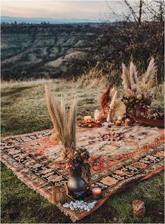 an outdoor table setting with flowers and feathers on it in the middle of a field