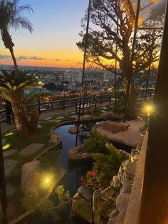 the sun is setting over a small pond and palm trees in front of a cityscape