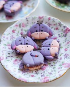 some cookies that are shaped like animals on a flowered plate with pink and purple frosting