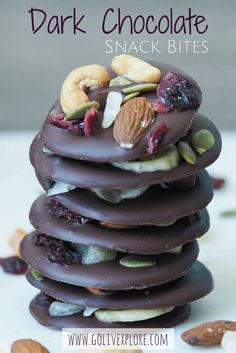 a stack of chocolate covered cookies with nuts and dried fruit on top, in front of the words dark chocolate snack bites