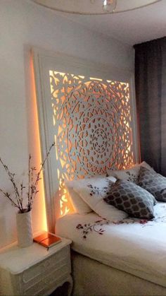 a white bed sitting under a window next to a vase with flowers on top of it