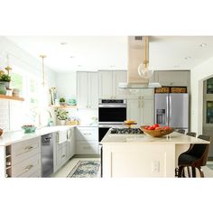 a kitchen with an island, stove and sink in the center is white cabinets and stainless steel appliances