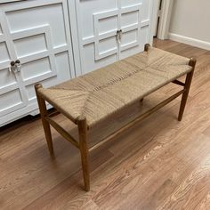 a wooden bench sitting on top of a hard wood floor next to white cupboards