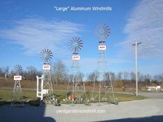 three windmills are standing in the middle of a parking lot with signs on them