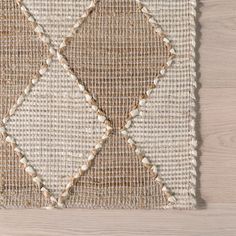 an area rug with white and brown squares on it, sitting on a wooden floor