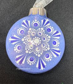 a blue glass ornament with white and purple designs