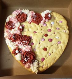 a heart shaped cake in a box decorated with flowers and icing on the inside