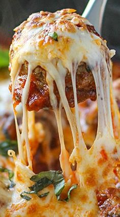 a close up of a slice of pizza being lifted with a fork from the casserole dish