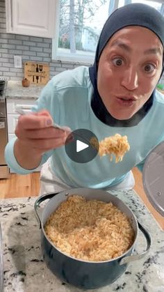 a woman holding a spoon in front of a pot filled with macaroni and cheese