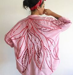 a woman wearing a pink jacket with red leaves on it