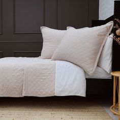 a bed with white sheets and pillows on top of it next to a night stand