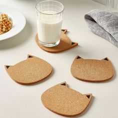 four coasters with cats on them next to a glass of milk and plate of waffles