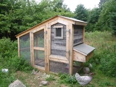 a chicken coop in the middle of a field with rocks and trees around it,