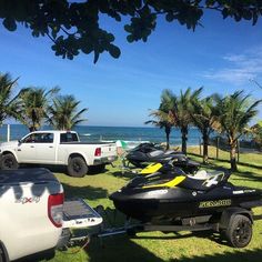 there are many vehicles parked on the grass by the beach