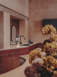 a sink and counter in a room with flowers on the counter top next to it